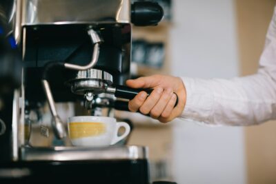 A barista prepares coffee using an espresso machine. Close-up of a man preparing coffee in a cafe.